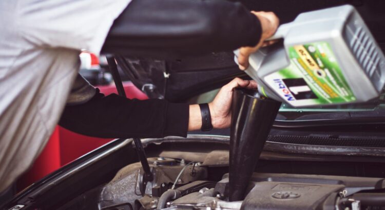 man refilling motor oil on car engine bay